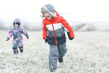 Kinder laufen über gefrorene Wiese